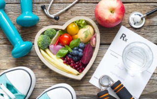 Image of healthy foods in a heart shaped bowl, weights, sneakers, stethoscope