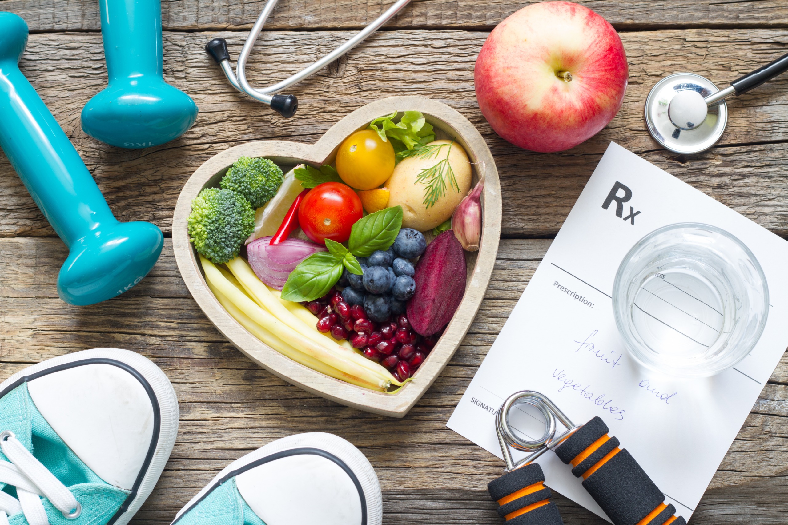 Image of healthy foods in a heart shaped bowl, weights, sneakers, stethoscope