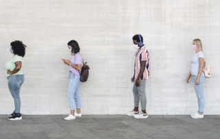 People in line standing 6 feet apart, each wearing a cloth face covering.