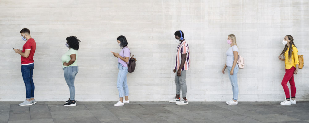 People in line standing 6 feet apart, each wearing a cloth face covering.